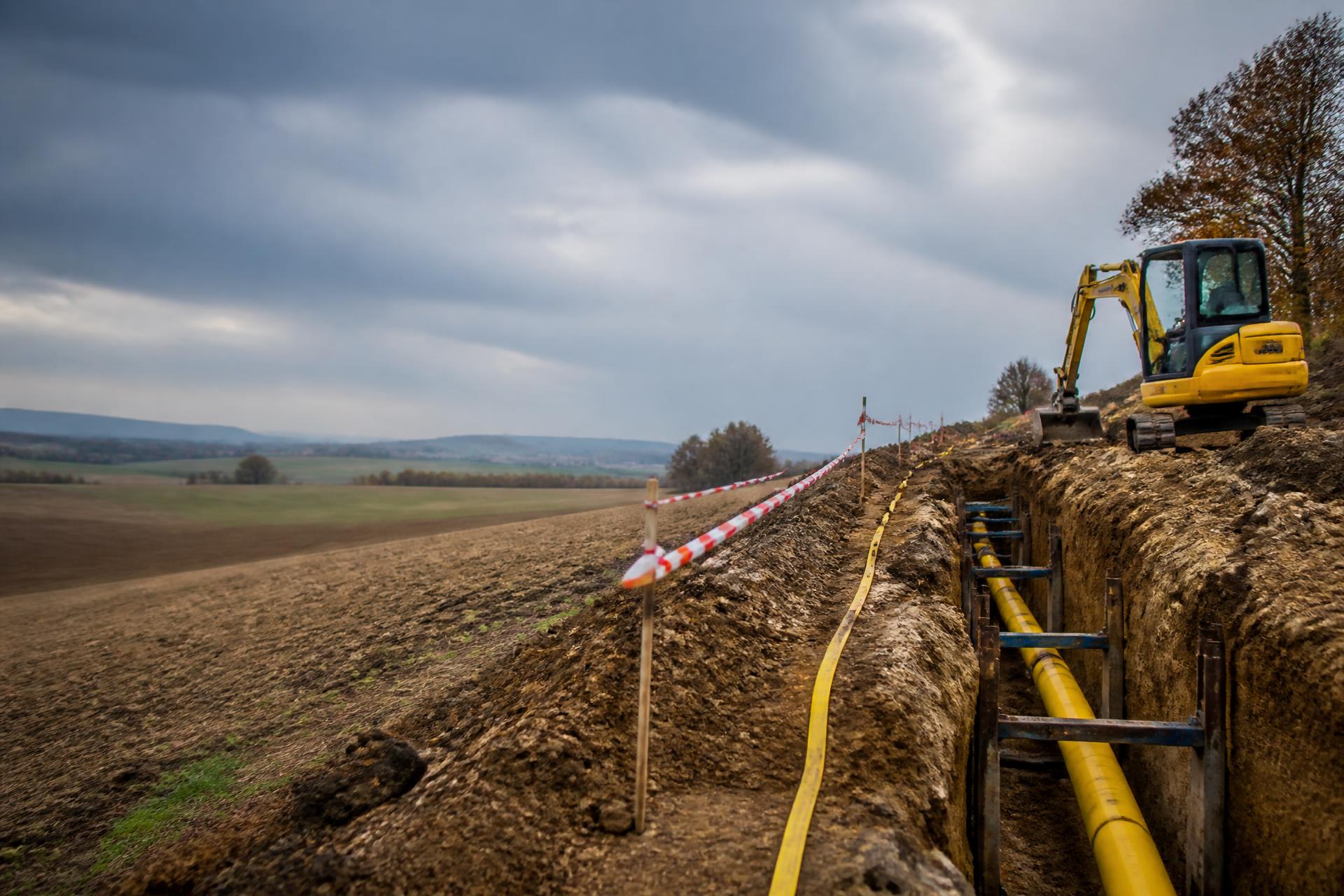 Výstavba plynovodu – žluté plynové potrubí v otevřeném výkopu, jižní Morava